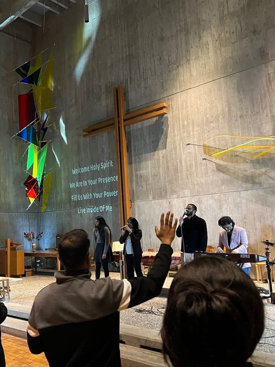 The worship team leading with keyboard and microphones beneath the cross